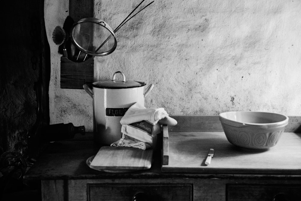 a wooden table topped with a bowl and a pot