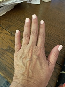 Close-up of perfectly polished hands with a soft pink manicure on a marble table.