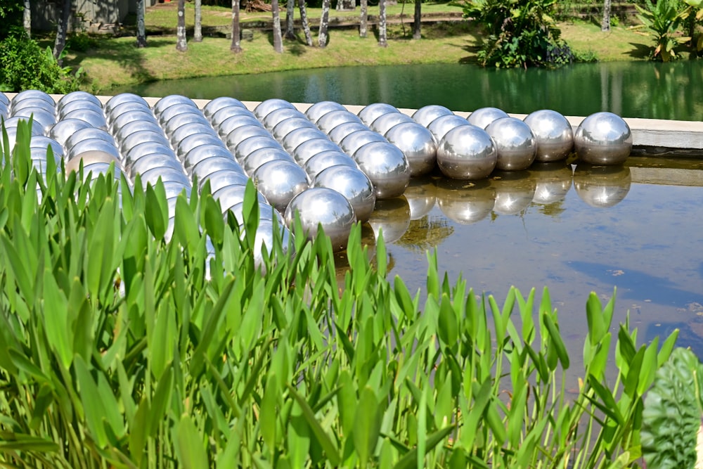 a row of silver balls sitting on top of a body of water
