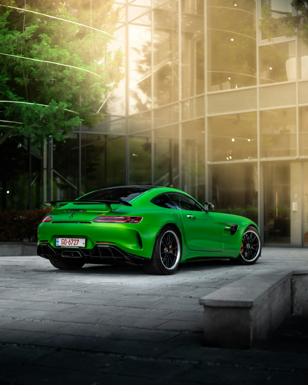 a green sports car parked in front of a building