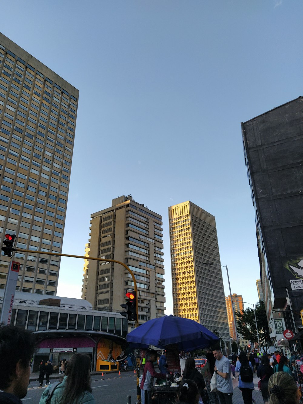 a group of people walking across a street next to tall buildings