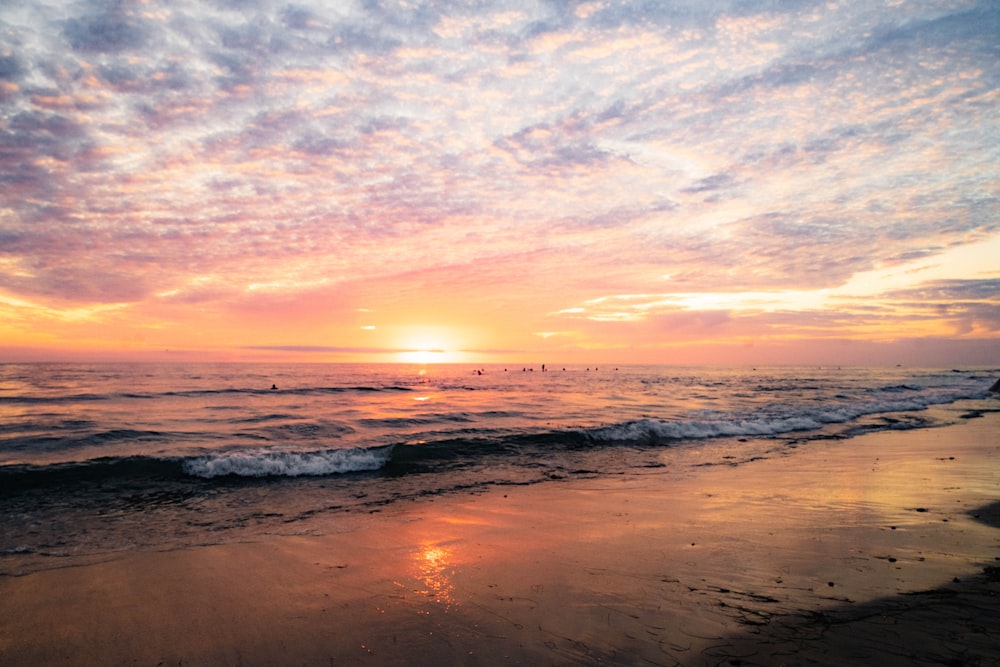 the sun is setting over the ocean on the beach