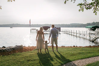 a man and a woman are standing on the grass by the water