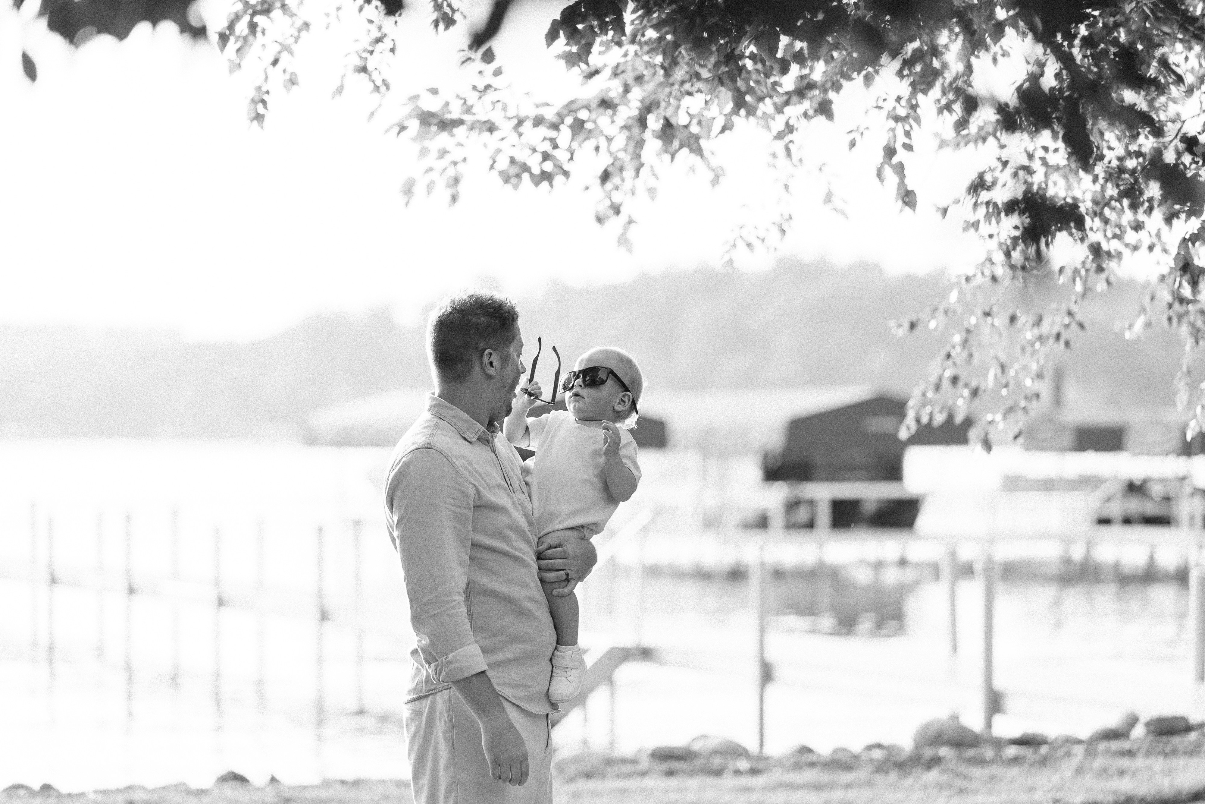 a man holding a baby under a tree