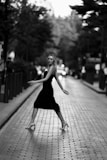 Model wearing a sleek, modern dress walking through a city street at sunset