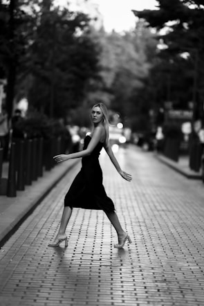 A stylish woman wearing a flowing black dress from zivoea, walking confidently on a city street at dusk.