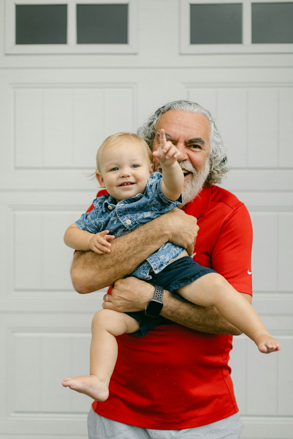 a man holding a baby in front of a garage door