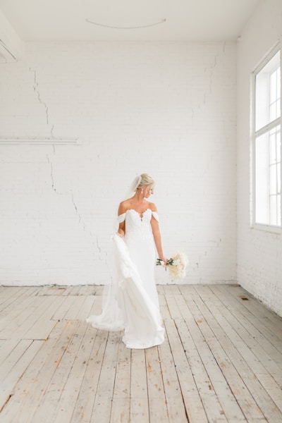 a woman in a white dress is standing on a wooden floor