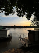 A serene view of the Ganga river at sunrise with boats near the homestay.