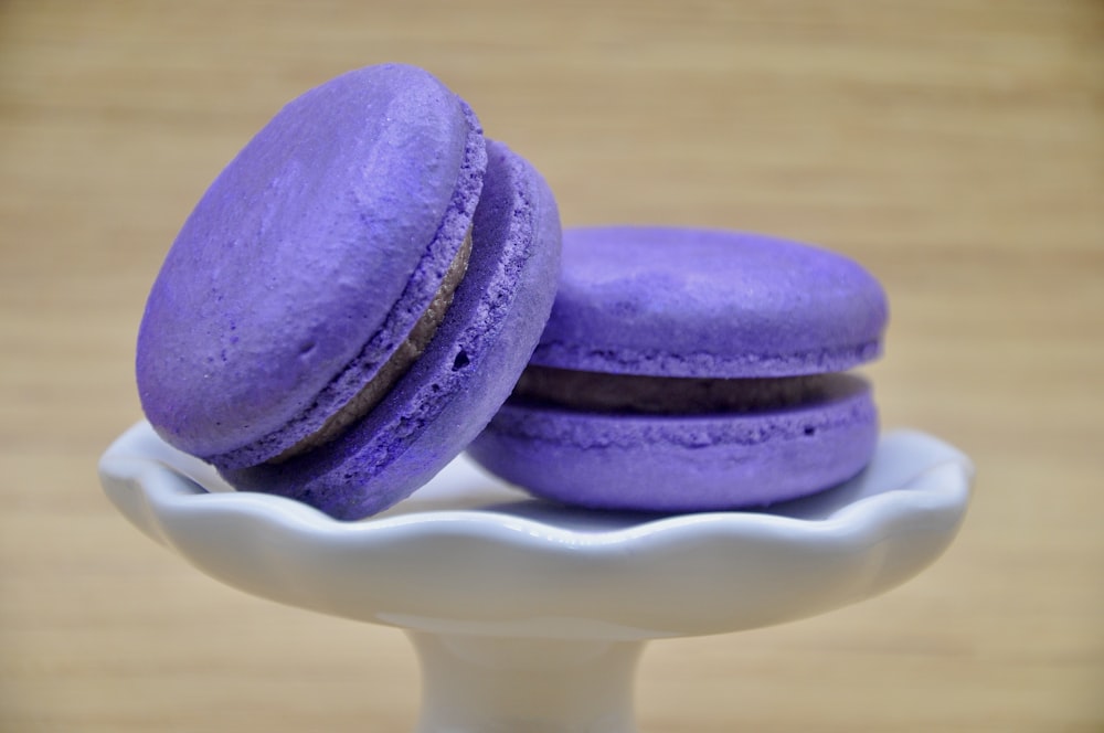 two purple macaroons sitting on top of a white plate
