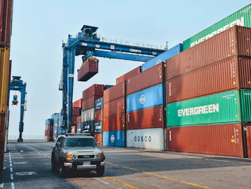 Workers loading vehicles onto a large shipping container at the port