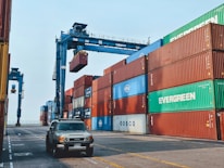 Stacks of used cars ready for export at a busy port.