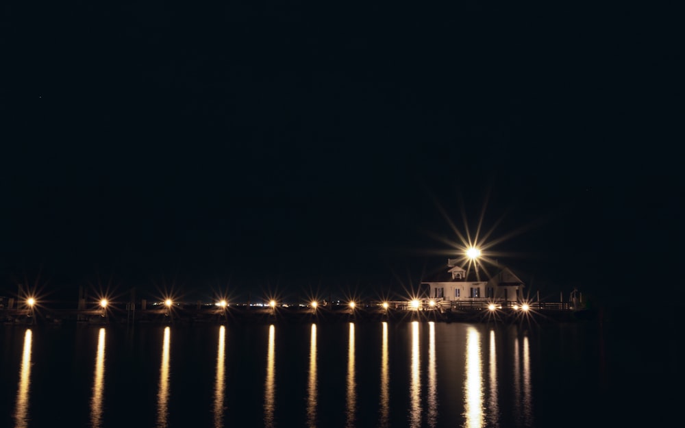 a lighthouse is lit up at night on the water
