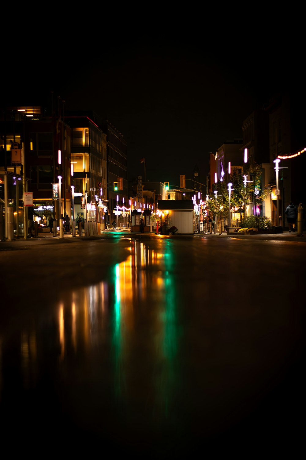 a city street at night with lights reflecting in the water