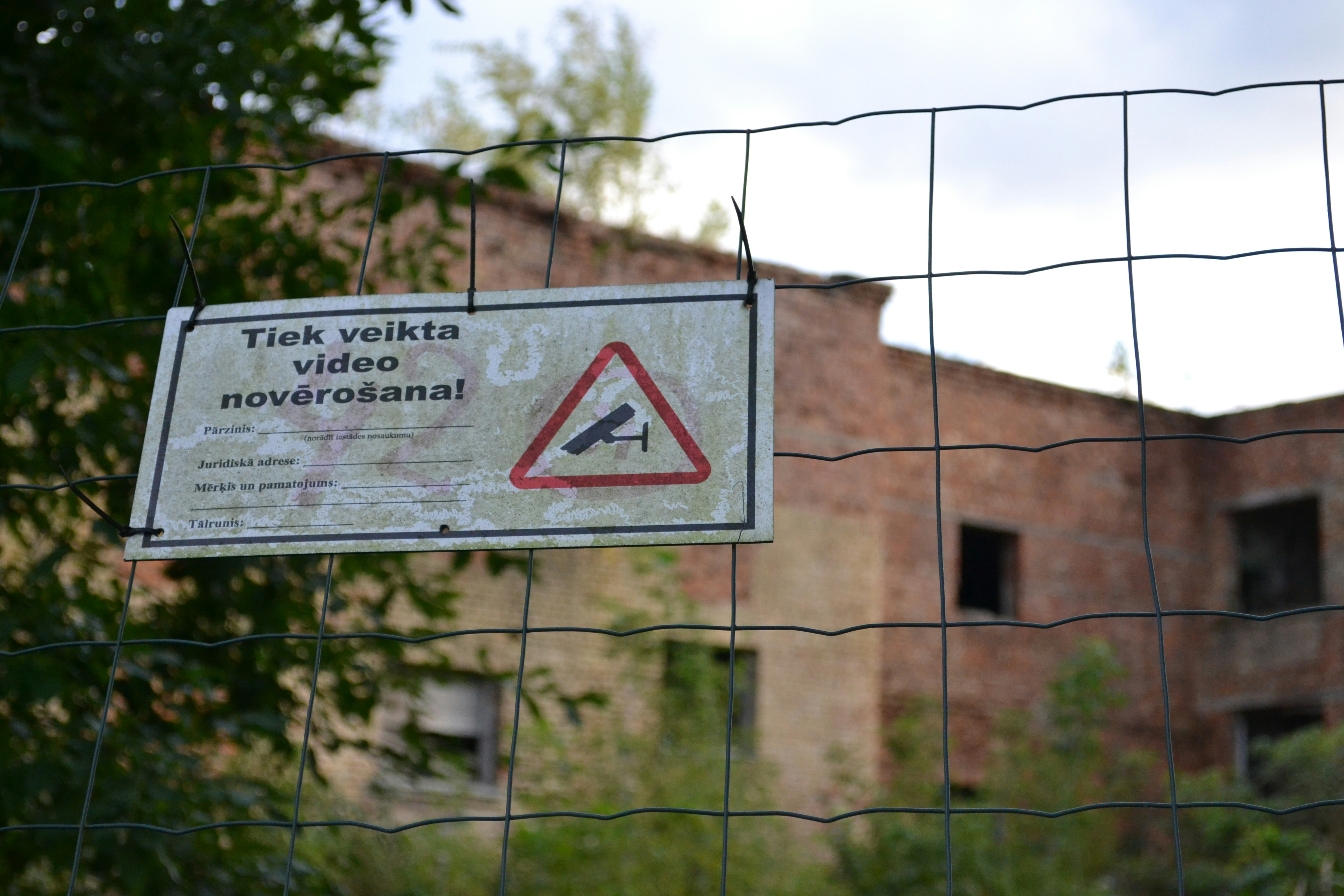 a sign is posted on a fence near a building