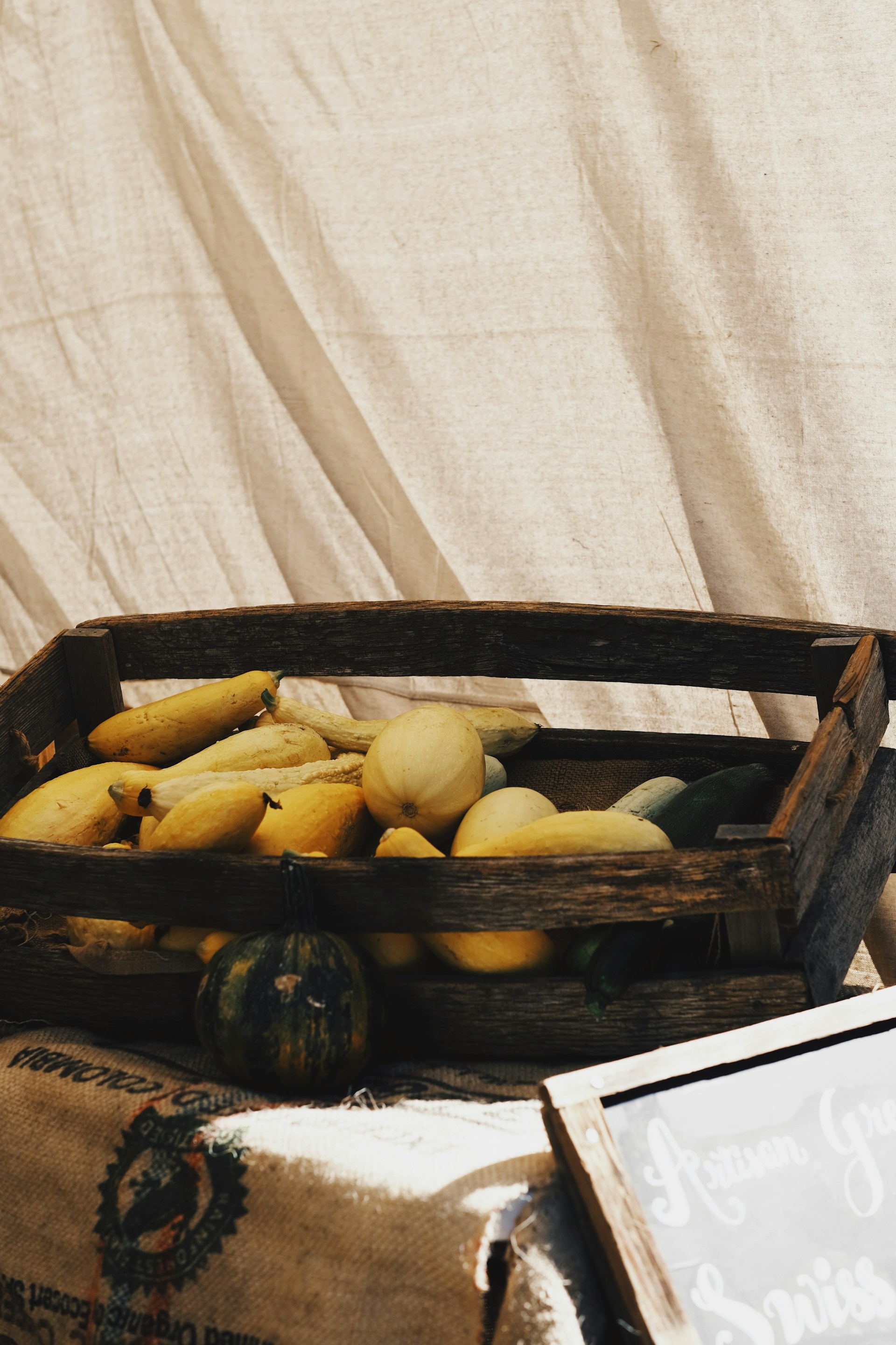 Freshly harvested cassava and yams piled beside a wooden crate, bathed in warm afternoon light.