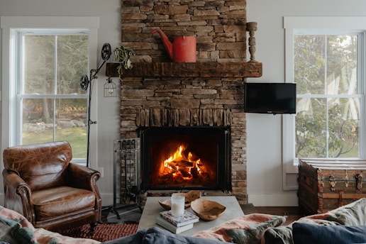 A cozy living room with a blue and red color scheme, featuring a warm fireplace and neatly arranged plumbing tools on a side table.