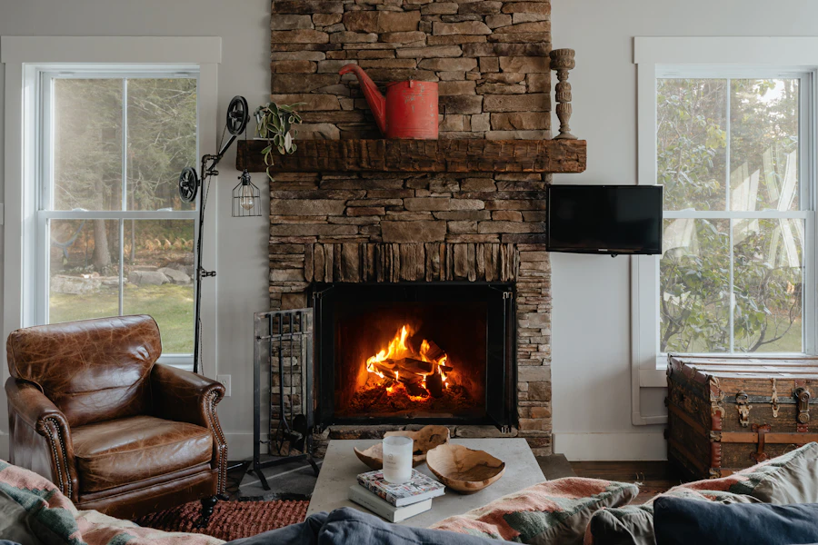 Warm living room with a lit stone fireplace and leather armchairs on a winter evening