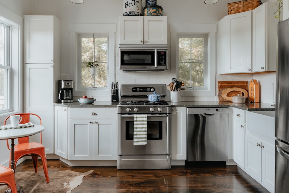 una cocina con gabinetes blancos y electrodomésticos de acero inoxidable