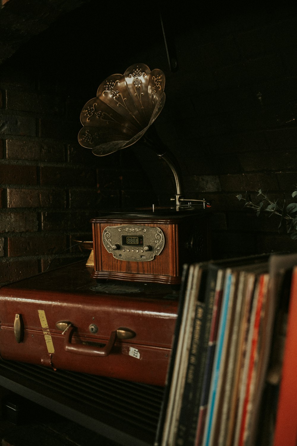 a red suitcase sitting on top of a stack of records