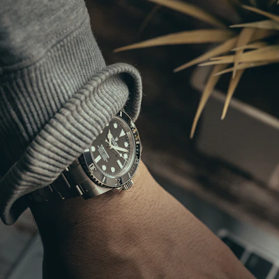 A wrist wearing a Royal Pop Swatch x Audemars Piguet watch while typing on a laptop, highlighting the elegance and style.