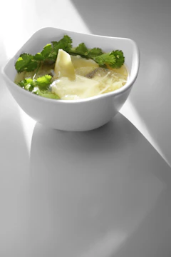 A softly lit restaurant interior with a steaming bowl of soup and a photographer capturing the scene.