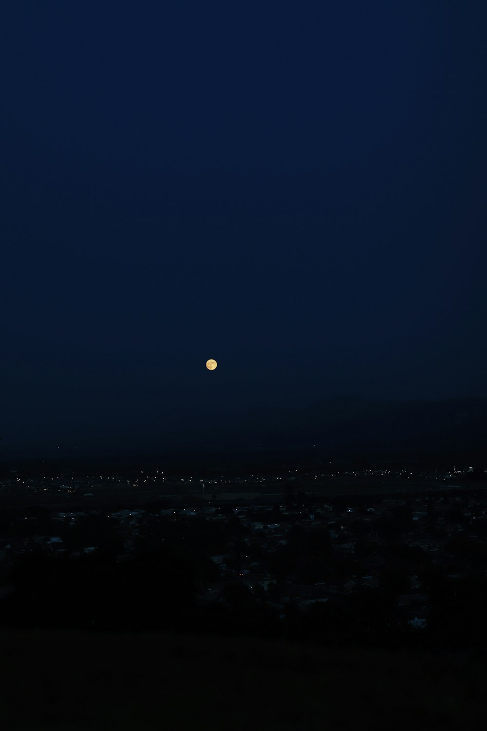 a full moon is seen in the sky above a city