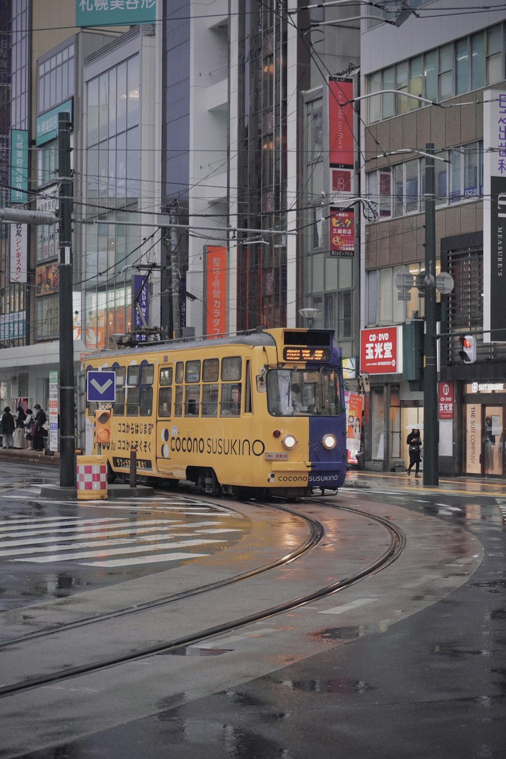 a yellow bus driving down a street next to tall buildings