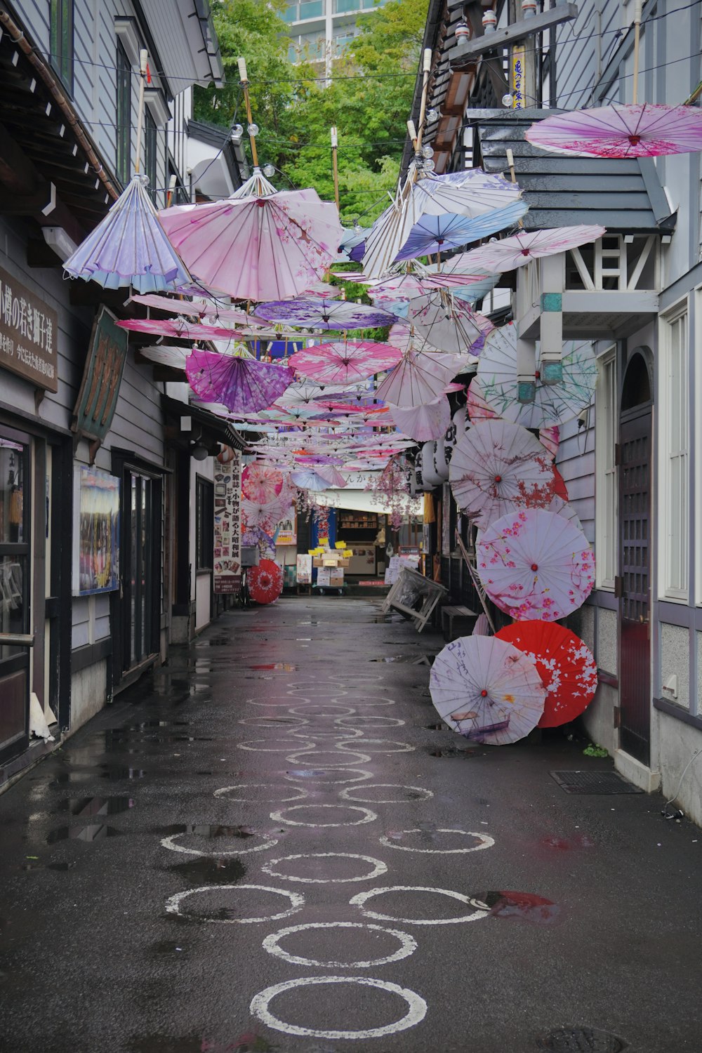 a narrow street with umbrellas hanging from the ceiling