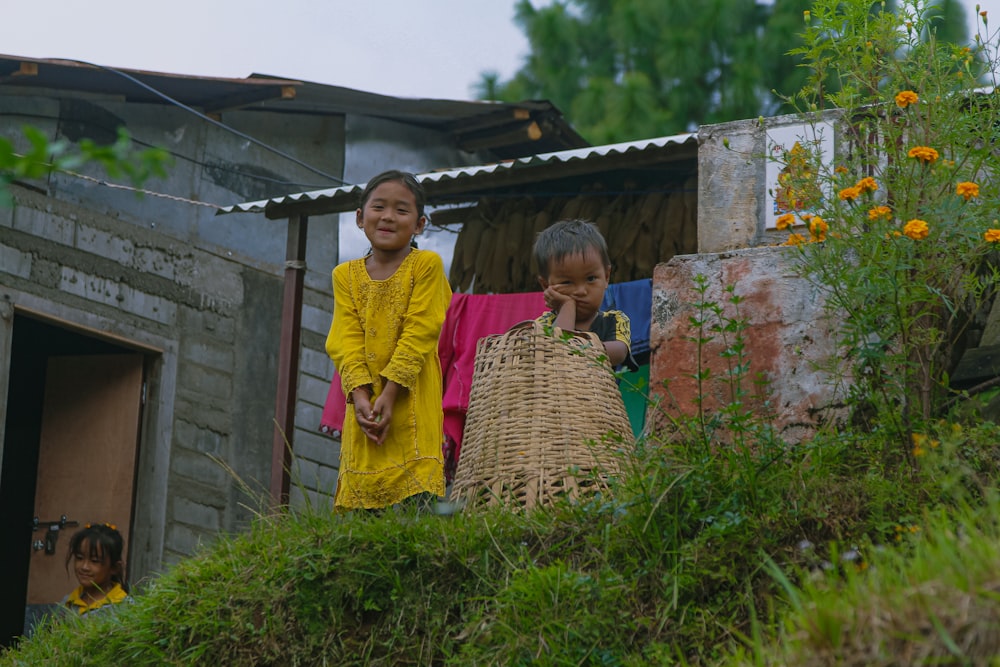 a couple of kids standing on top of a grass covered hillside