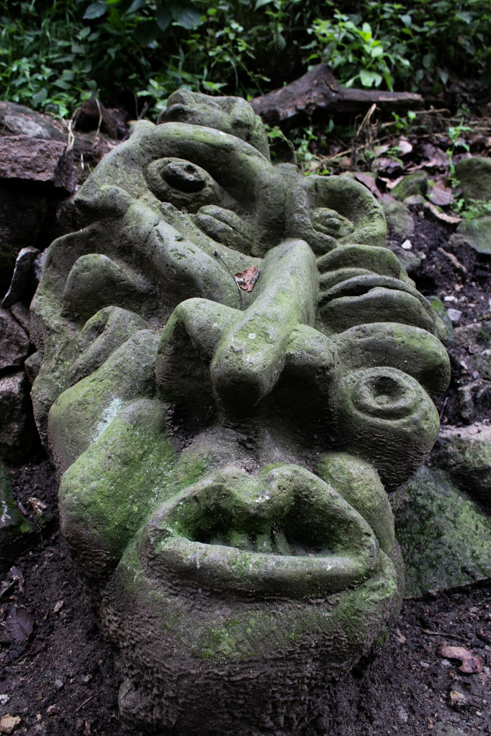 una statua di pietra di un volto a terra