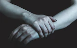 Close-up of hands intertwined, bathed in natural anthracite shadow and warm light.