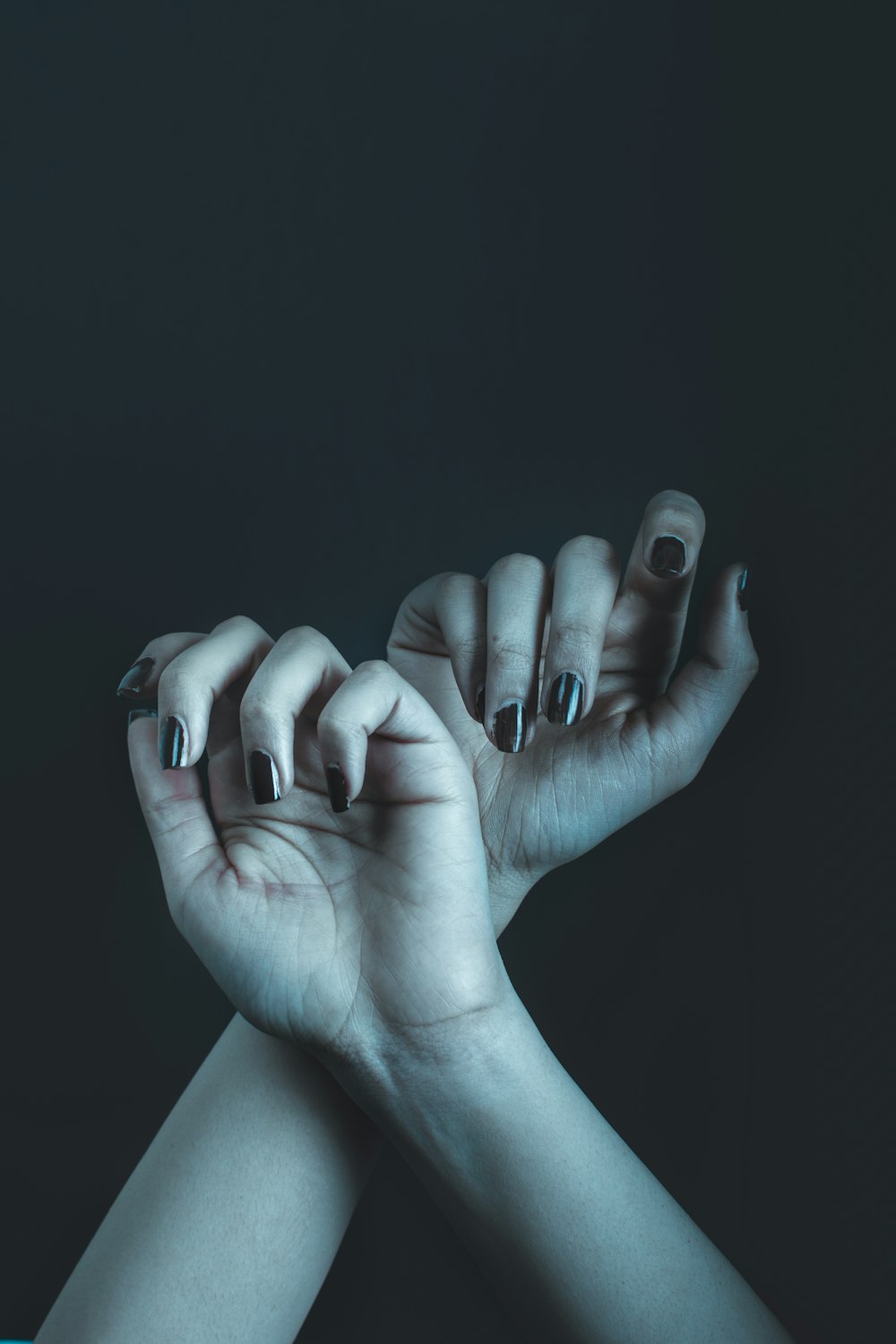 Dos manos con esmalte de uñas blanco y negro sosteniéndose