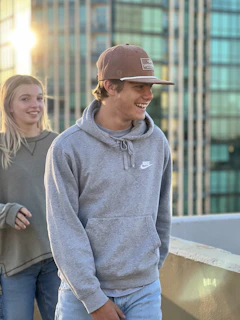 A candid street photo of two friends, one in a hoodie and the other in a t-shirt, laughing on an urban bridge at sunset.