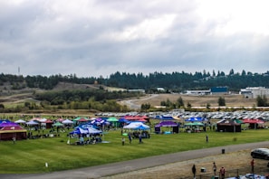 An aerial view of a large outdoor event with tents and attendees.