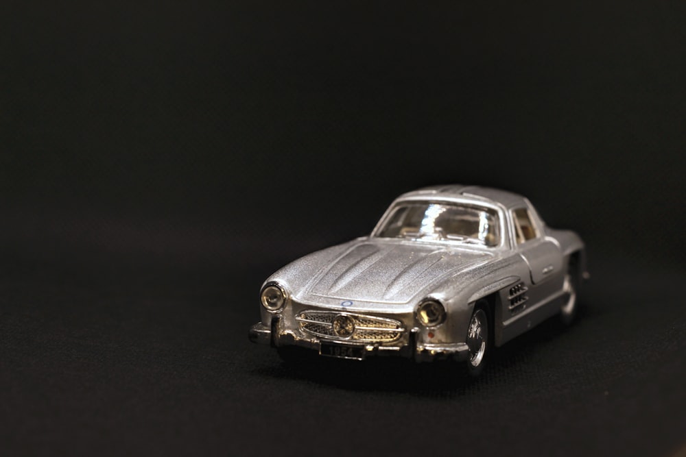 a silver toy car sitting on top of a table