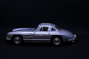 Close-up of a sleek 1:18 scale metallic silver classic muscle car model on a dark reflective surface