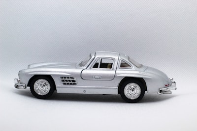 Close-up of a silver classic car model with polished finish and intricate wheels.