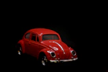 A close-up of a classic red vintage car model on a black display stand