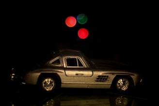 Close-up of a sleek metallic diecast car model reflecting soft ambient light on a dark background.