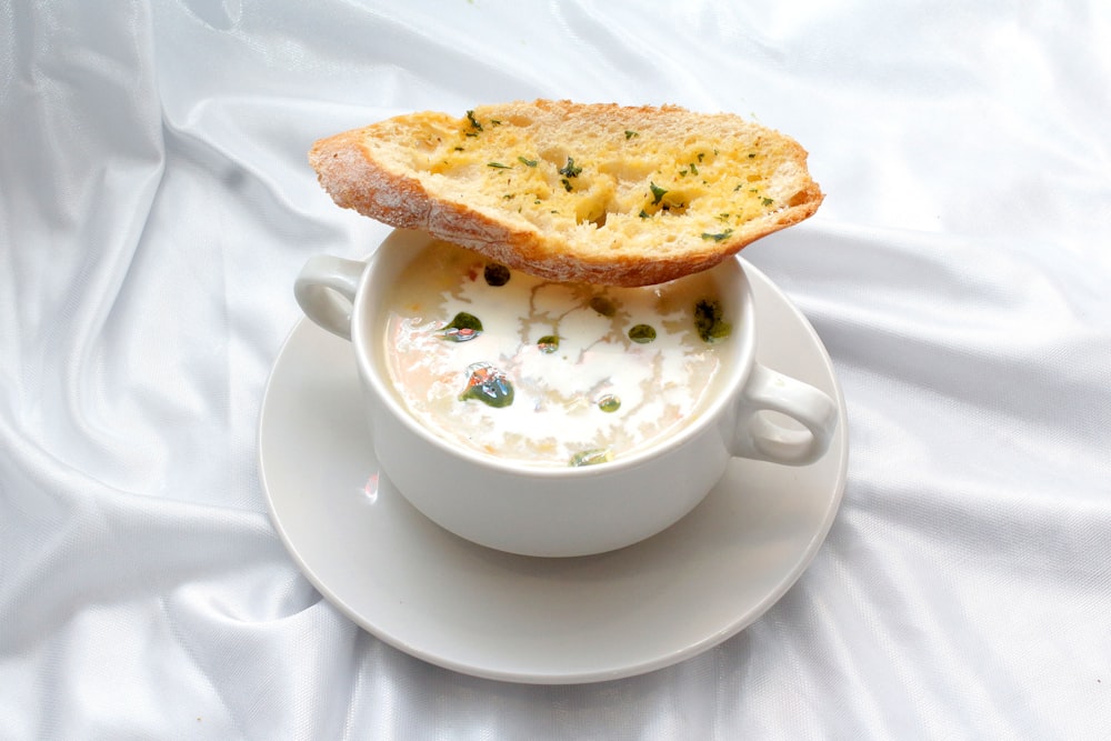 a bowl of soup with a piece of bread sticking out of it