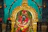 Close-up of colorful temple garlands draped over a traditional brass lamp.