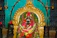 Close-up of colorful temple garlands draped over a traditional brass lamp.