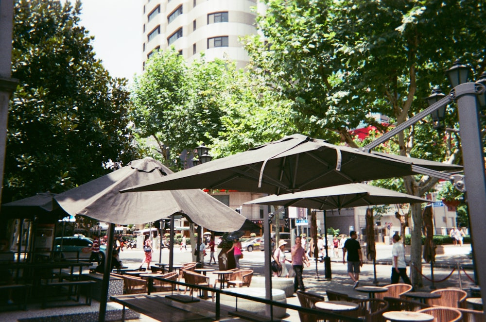 a group of tables with umbrellas on a city street