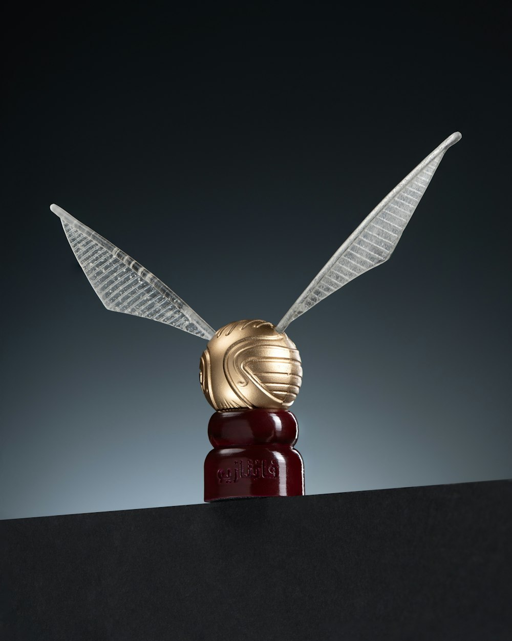 a gold and silver sculpture of two wings on top of a black surface