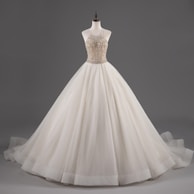 A mannequin displays an elegant white ball gown with a fitted bodice adorned with intricate beadwork and a voluminous layered skirt.