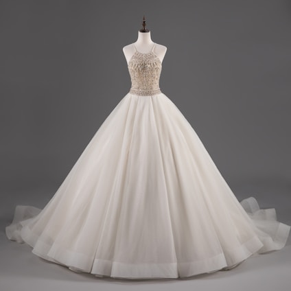 A mannequin displays an elegant white ball gown with a fitted bodice adorned with intricate beadwork and a voluminous layered skirt.