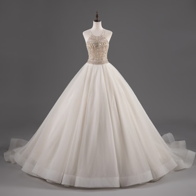 A custom-made gown with intricate beadwork showcased on a wooden dress form.