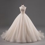 A luxurious, strapless ball gown with intricate lace detailing on the bodice, featuring a voluminous tulle skirt. The dress is displayed on a mannequin against a plain grey background.