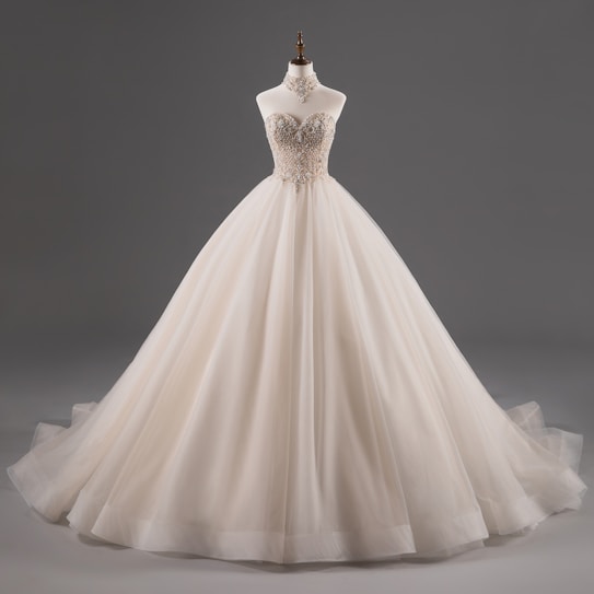A luxurious, strapless ball gown with intricate lace detailing on the bodice, featuring a voluminous tulle skirt. The dress is displayed on a mannequin against a plain grey background.